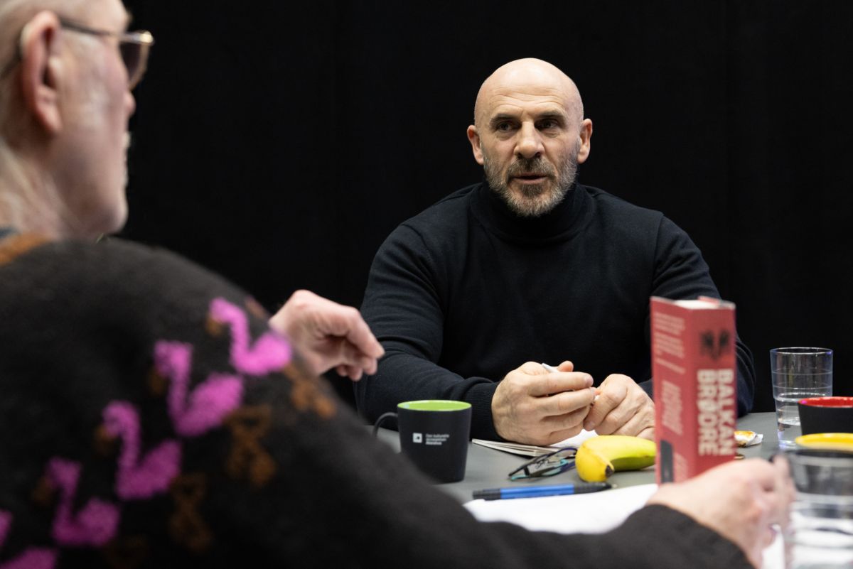 To menn sitter ved et bord og snakker sammen