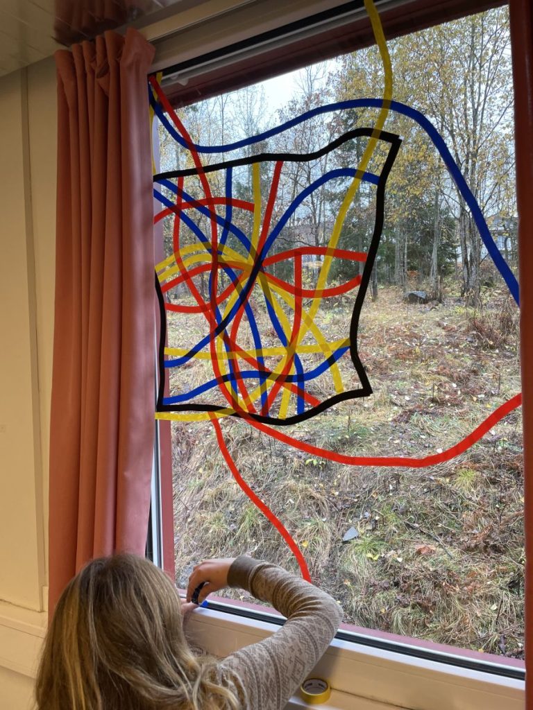En elev som lager kunst på et vindu av teip