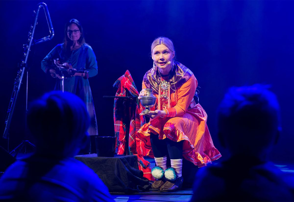 Kvinnelig, samisk sanger på scenen foran elever.