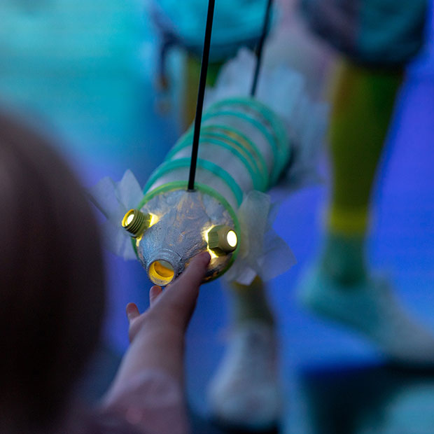 En barnehånd strekker seg etter en "fisk" i dukketeater.