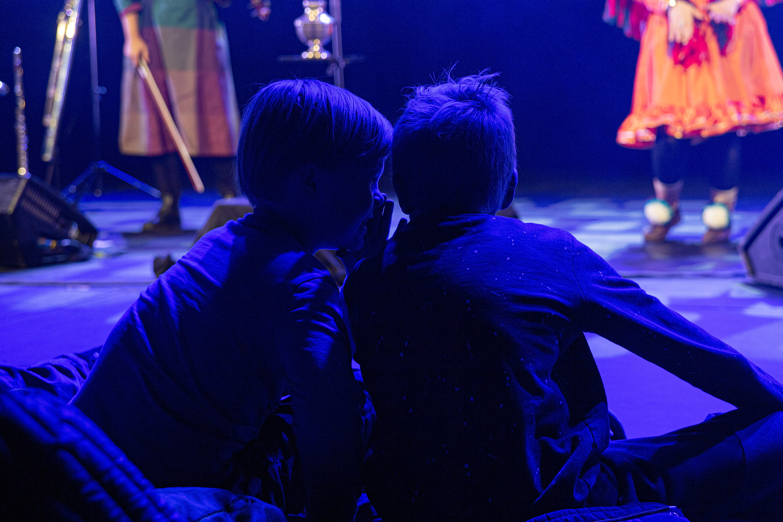 To gutter med ryggen til hvisker til hverandre foran en scene
