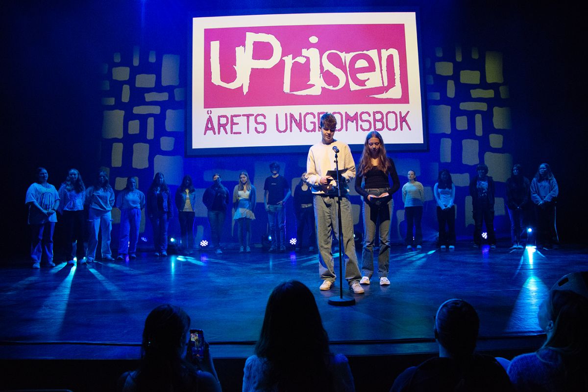 Barn på lyssatt scene som presenterer juryens begrunnelse for tildeling av U-prisen 2024.