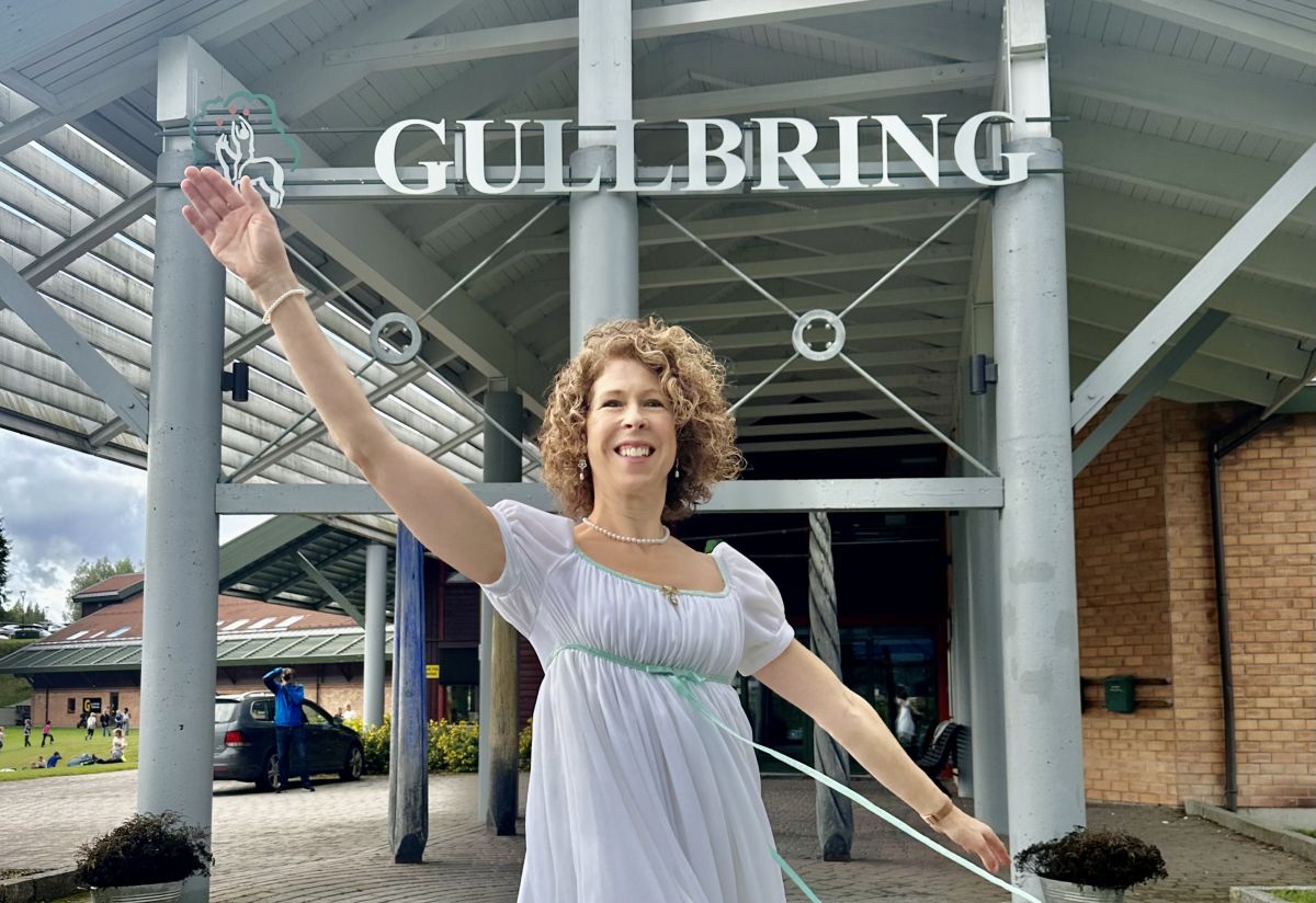 En danser i hvit kjole holder dansepositur framom Gullbring kulturhus