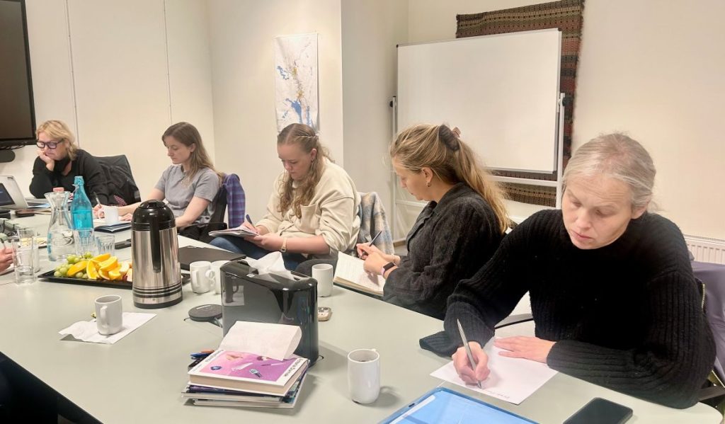 Fem personer sitter og skriver og tenker.