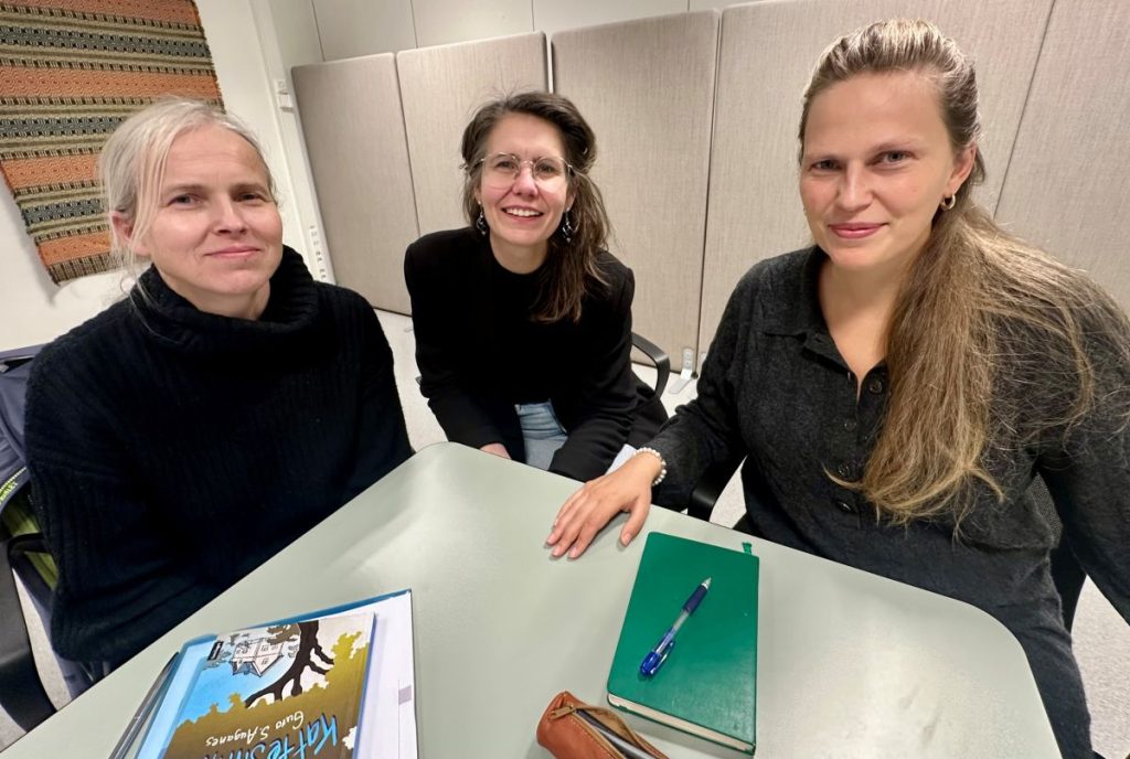 Tre kvinner smiler til kamera. 