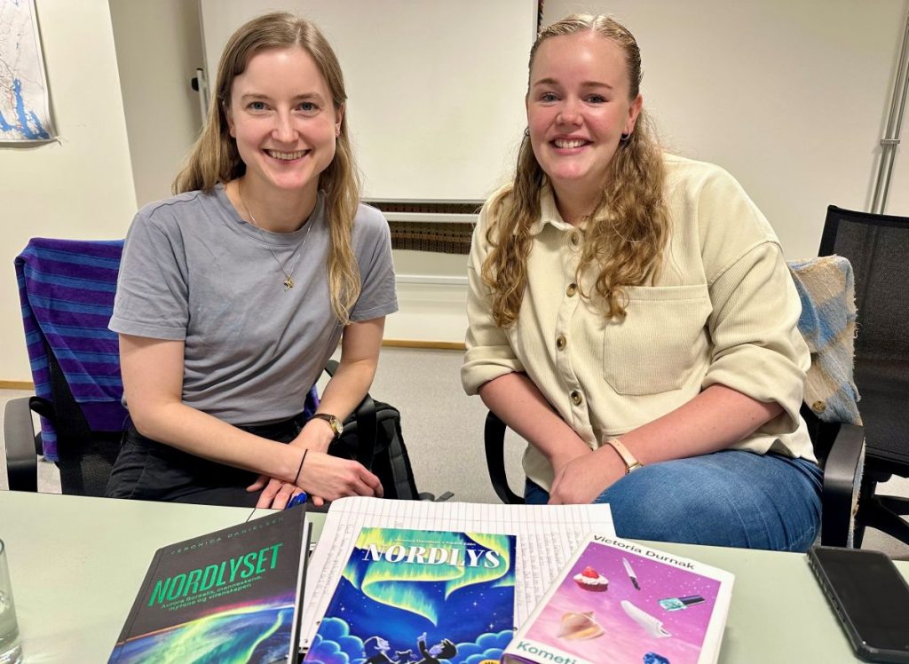 To kvinner viser fram bøker de har skrevet og er blide. 